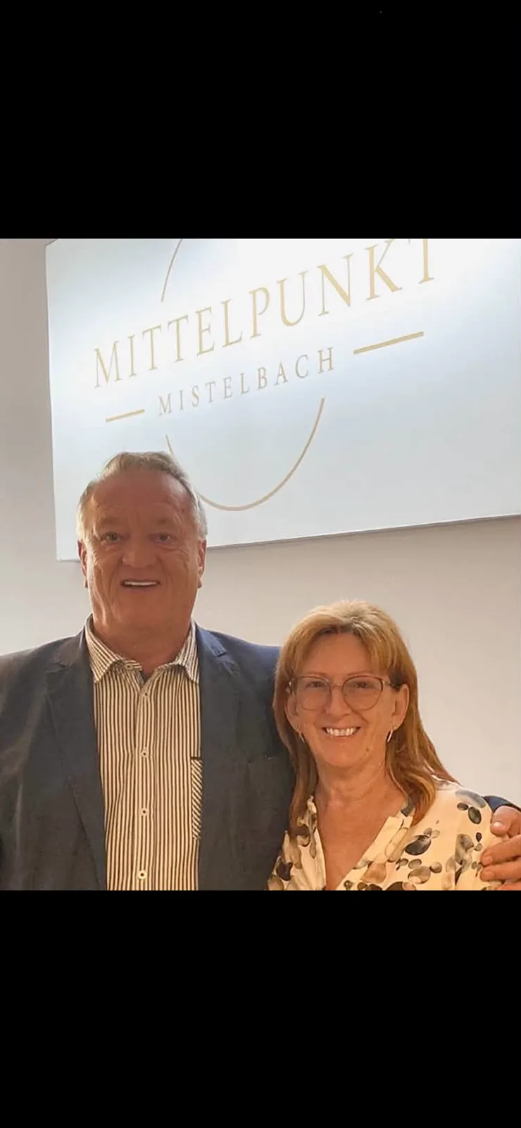 Zwei G&auml;ste vor dem Mittelpunkt-Mistelbach-Logo