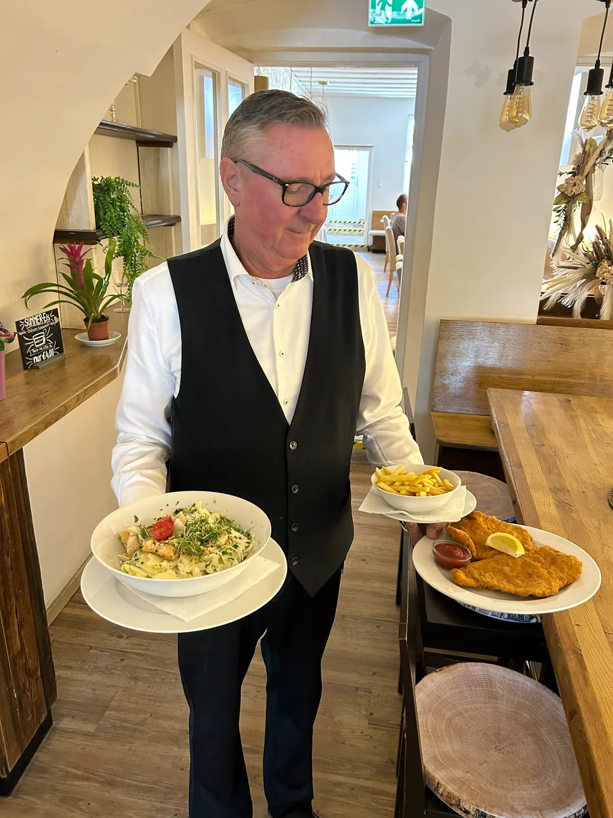 Service mit Schnitzel, Pommes und Salat im Gastraum
